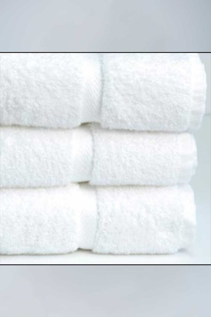 Hotel-Towels-27x54-Bath-Towel-White - Poltex International Inc Stack of white towels neatly folded and stacked on top of each other.